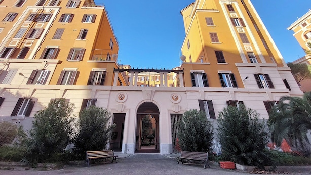 A yellow building with multiple windows and a central archway. - Domus Augustea San Giovanni Sunset Suites - Deluxe Suite Ottanivm (Roma)
