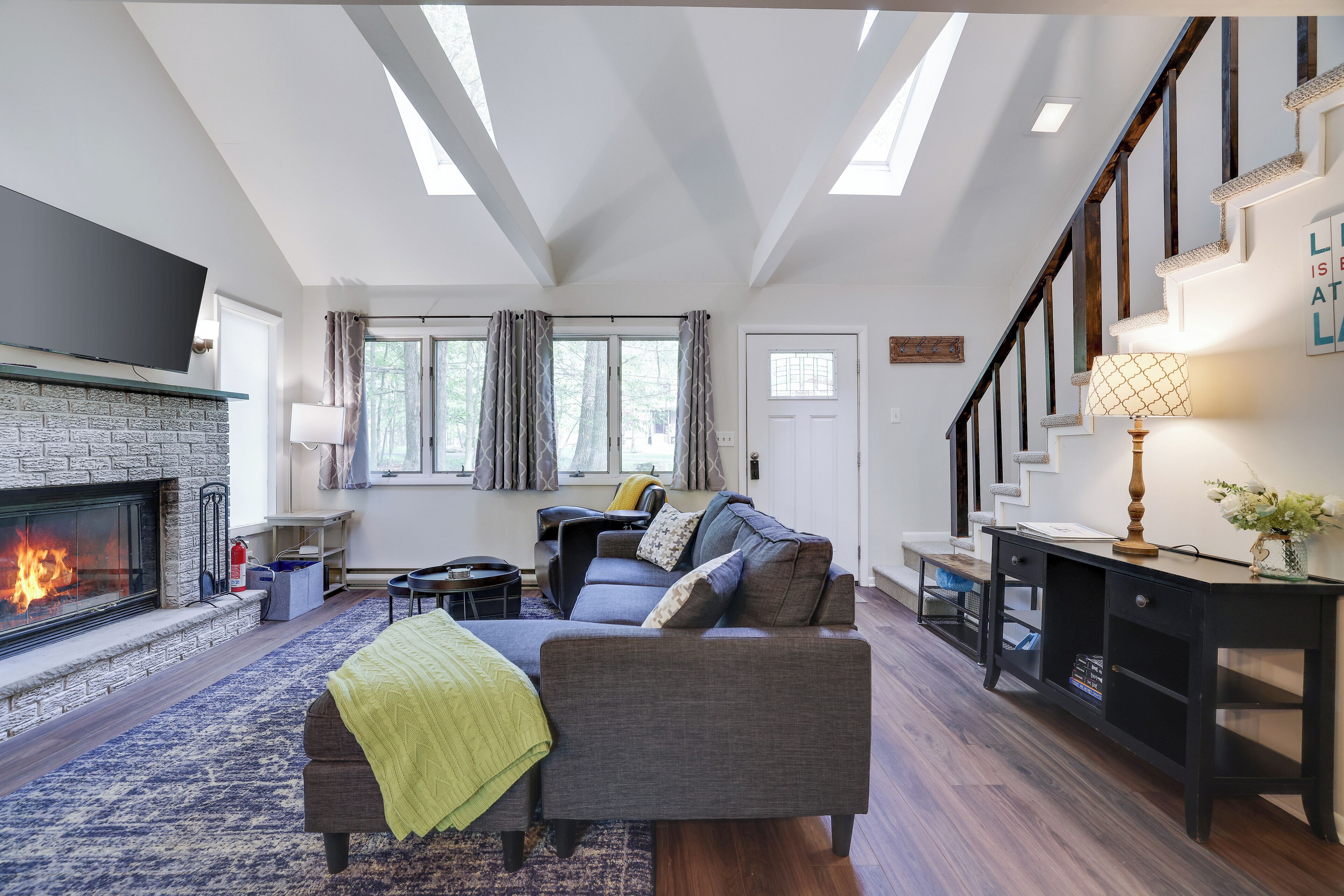 A modern living room with a fireplace, a sofa, a coffee table, and a staircase.