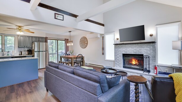 A spacious living area with a fireplace, a large sofa, a dining table, and a kitchen area with a blue island.