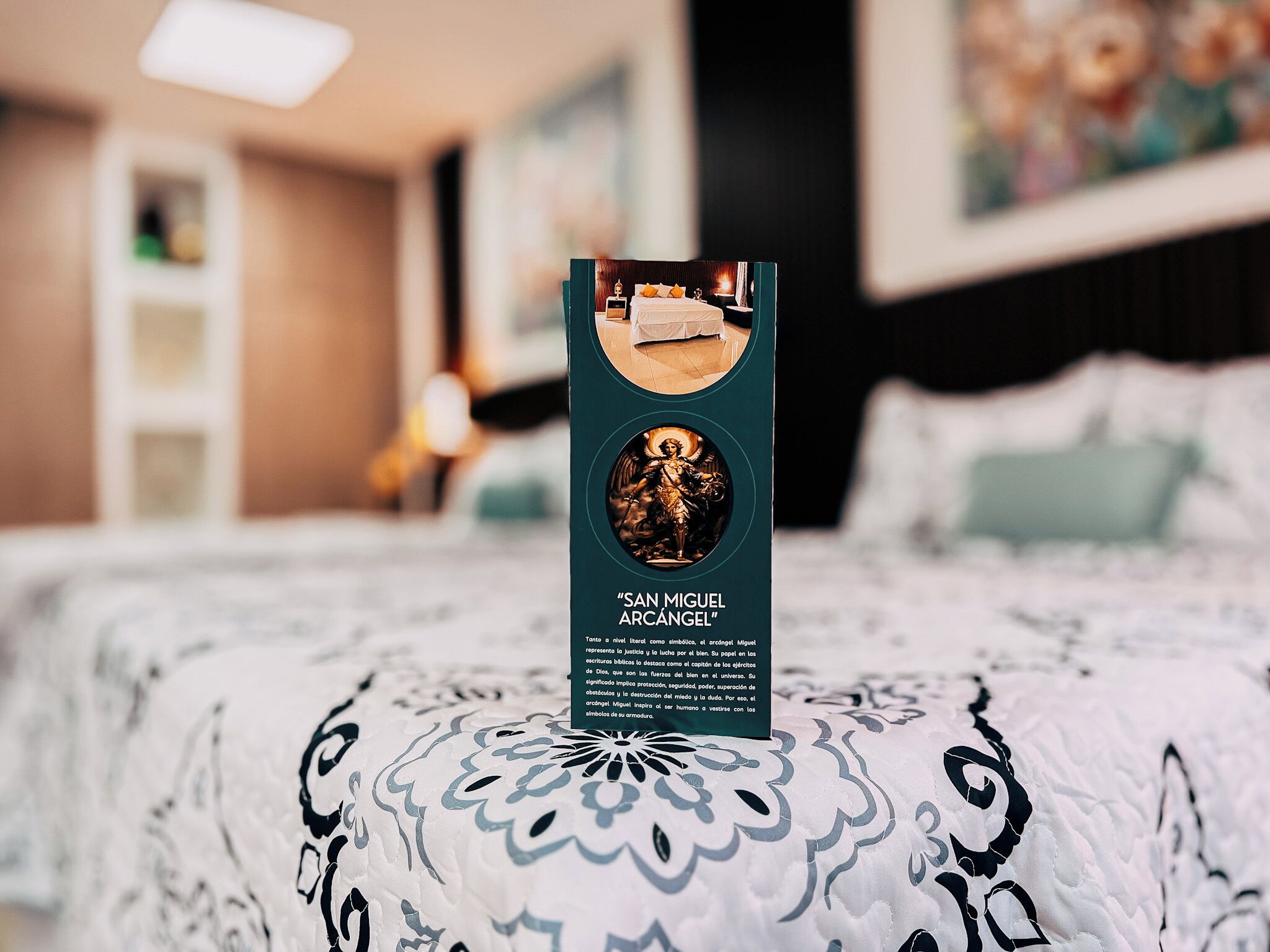 A brochure titled "SAN MIGUEL ARCÁNGEL" on a bed with a patterned bedspread.