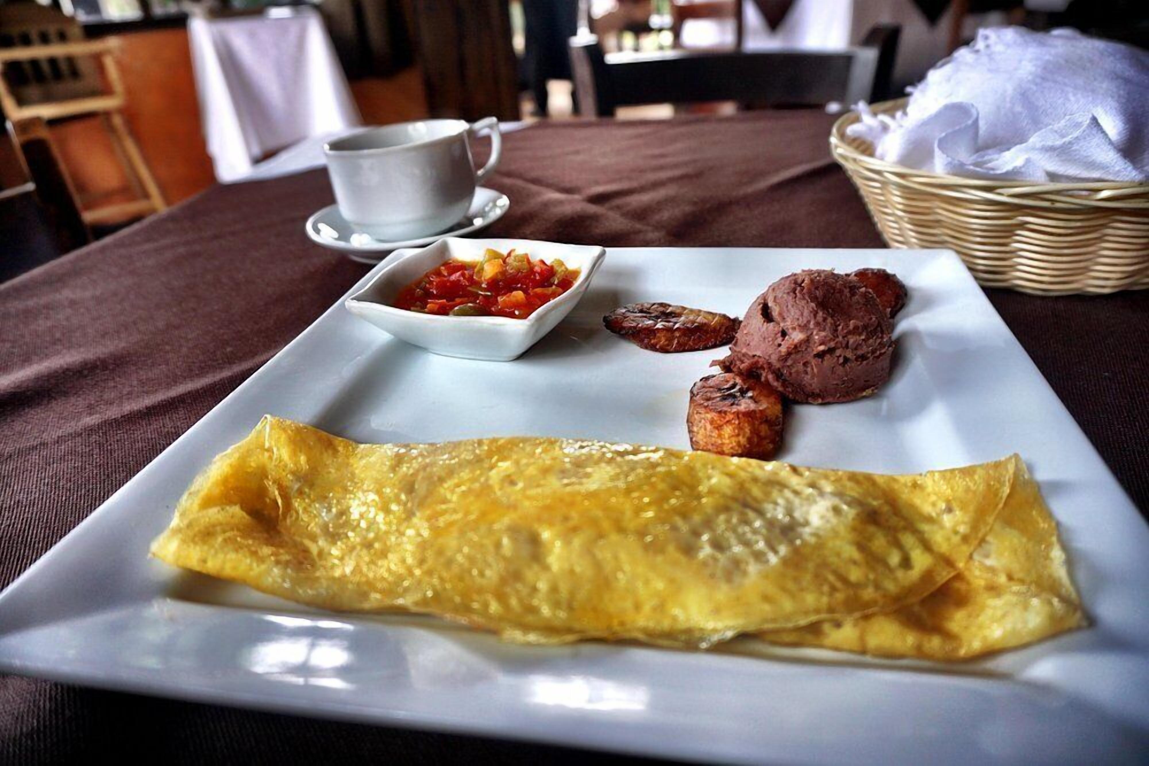 Une assiette de petit-déjeuner comprenant une omelette, deux œufs au plat et une portion de salsa.