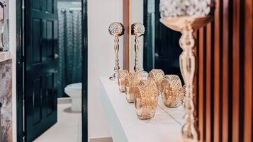 A bathroom with a marble countertop, a mirror, and a door leading to another room.