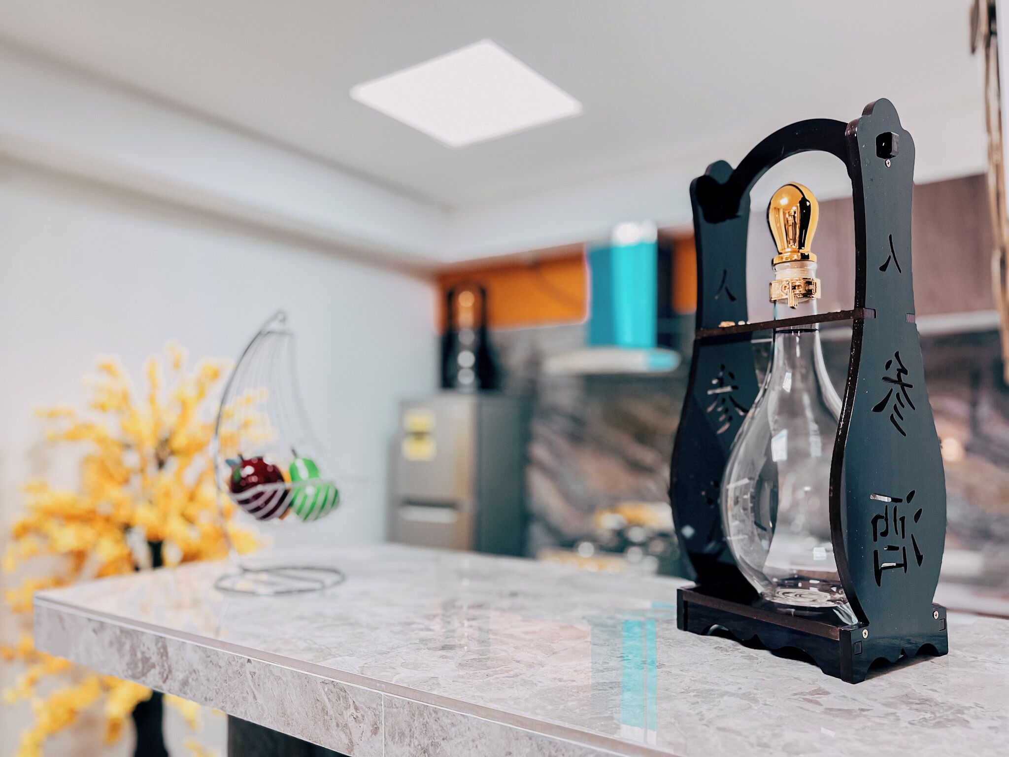 Uma bancada de cozinha com um jarro de vidro decorativo e uma cesta de frutas pendurada.