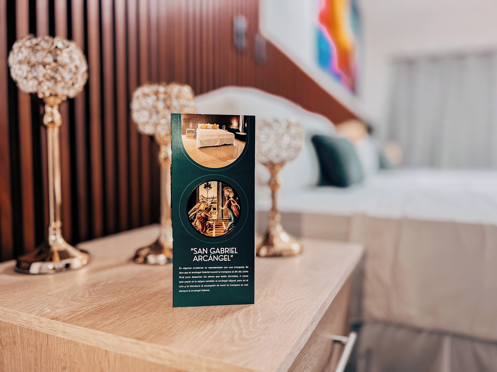 Un folleto titulado "SAN GABRIEL ARCÁNGEL" sobre una mesa de madera con lámparas decorativas.