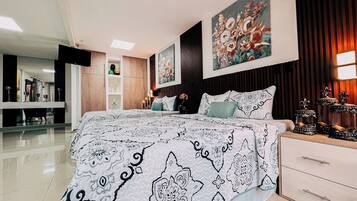 A modern bedroom with a large bed, a dresser, and a painting on the wall.