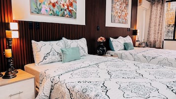 A bedroom with two beds, a nightstand, a dresser, and wall art.