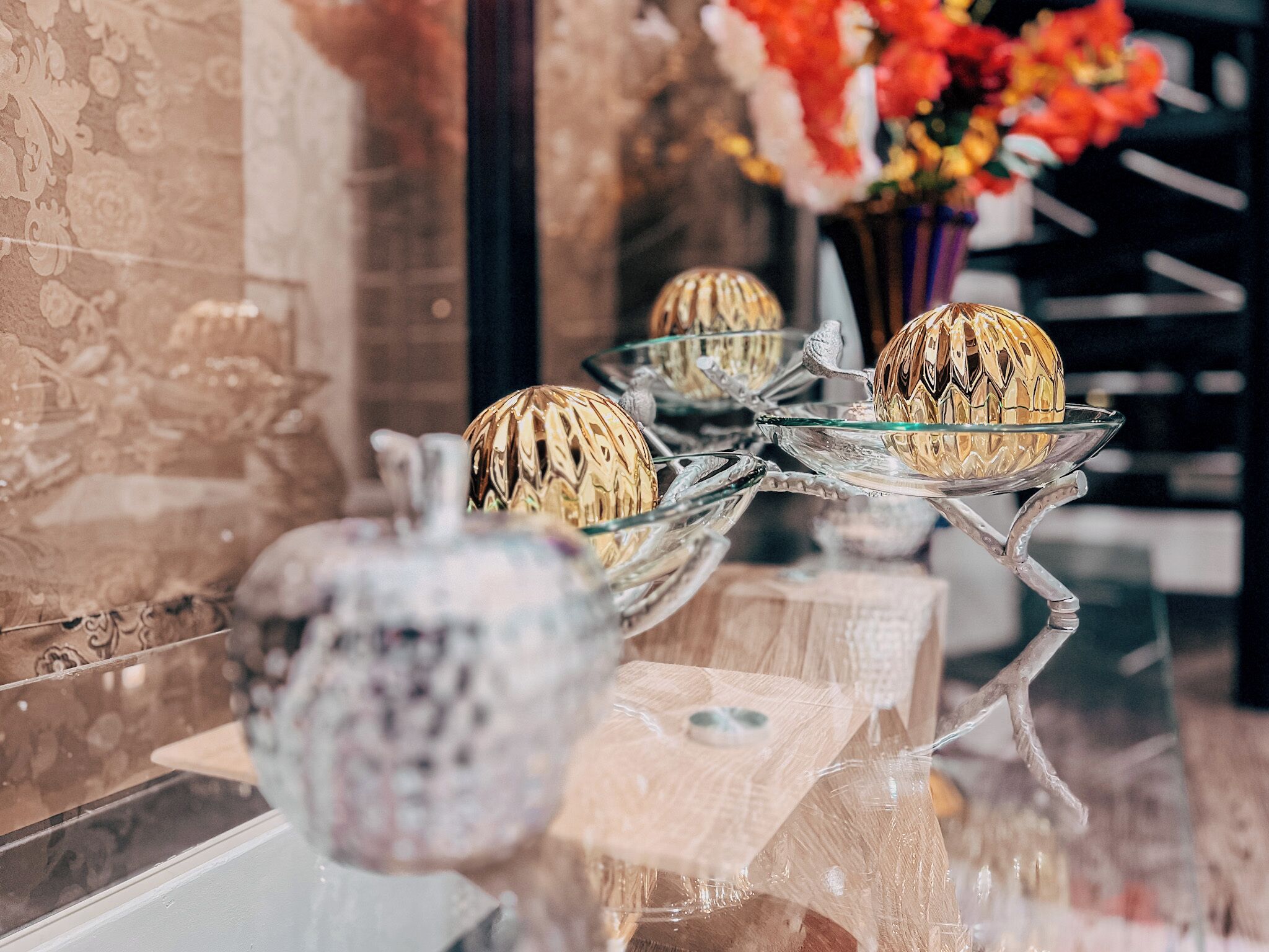 A glass display case with decorative items, including a vase and a golden ornament, on a reflective surface.