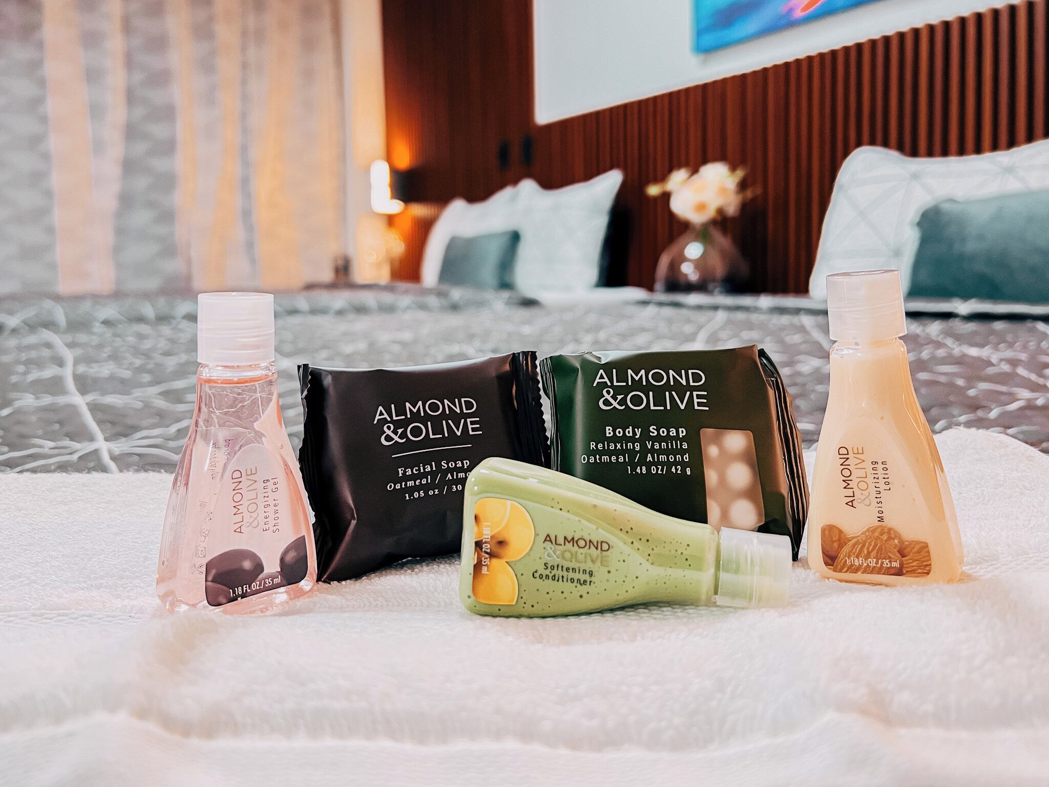 A selection of Almond & Olive body care products on a bed with a white textured cover.