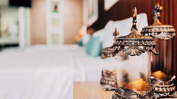 A room with a bed, a wooden table with ornate candle holders, and a blurred background suggesting a hotel setting.