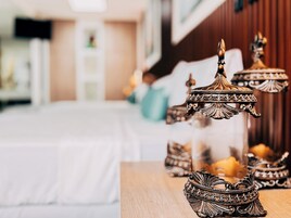 Una habitación con una cama, una mesa de madera con candelabros ornamentados y un fondo desenfocado que sugiere un ambiente de hotel.