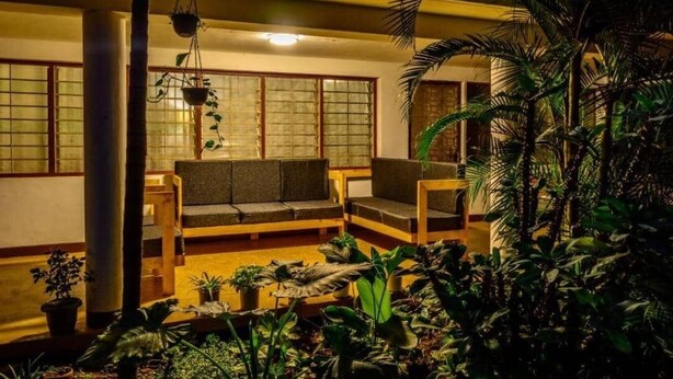 A traditional Japanese-style room with tatami flooring, a low wooden table, and a sofa. - Bustani Luxury Homestay (Moshi)