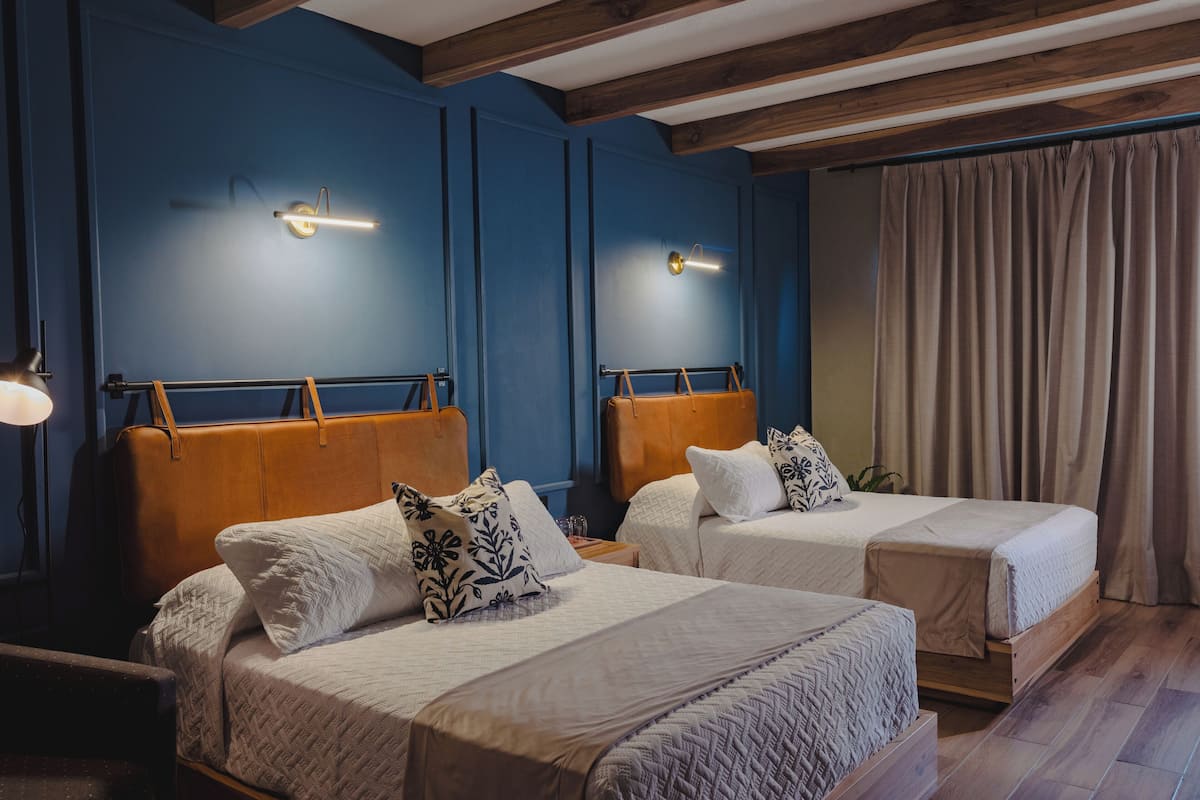 Ett hotellrum med två sängar, trägavlar och sänglampor.