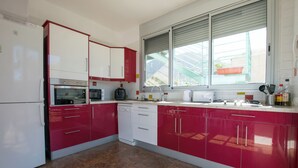 Une cuisine avec des meubles de couleur rouge et blanche, un lave-vaisselle, un four à micro-ondes et une fenêtre donnant sur un paysage verdoyant.