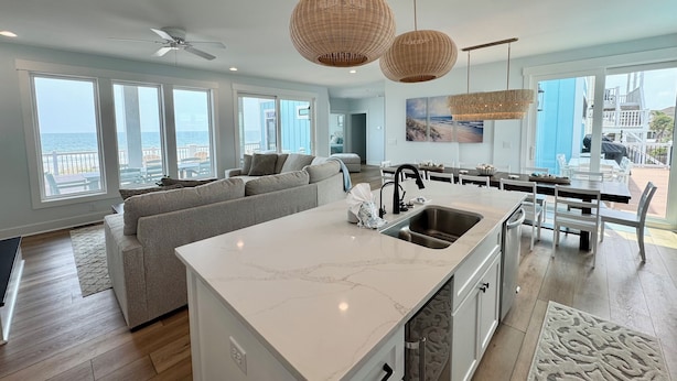 A modern kitchen with a large island, white marble countertop, and a view of the ocean through large windows. - NewBeach Front Home,6bd,6.5ba Elevator,Pool,Spa!! (Ocean Isle Beach)