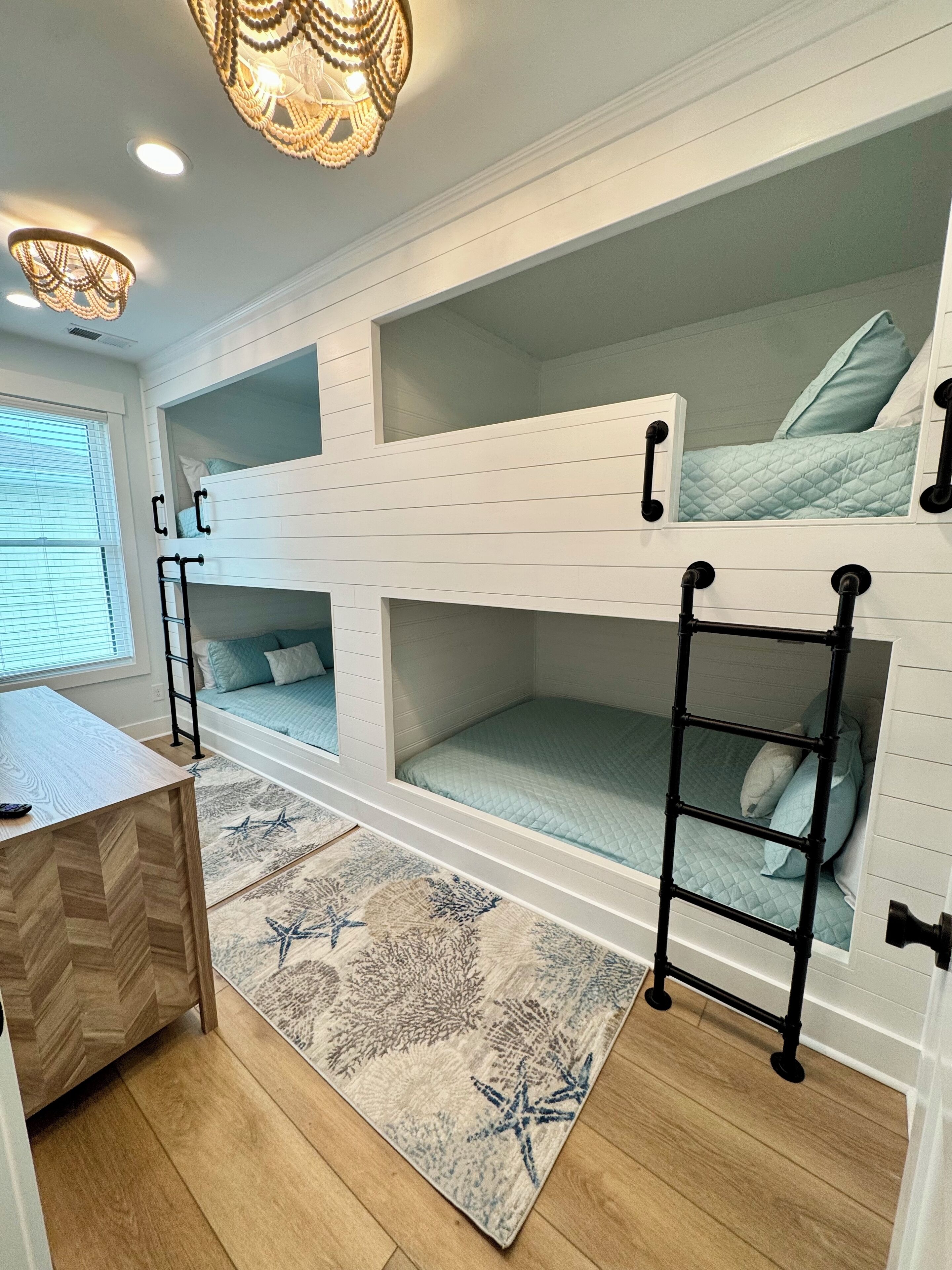 A bunk bed room with a desk and a patterned rug.