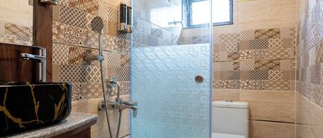 A modern bathroom with a glass shower enclosure, a wooden vanity, and patterned tiles.