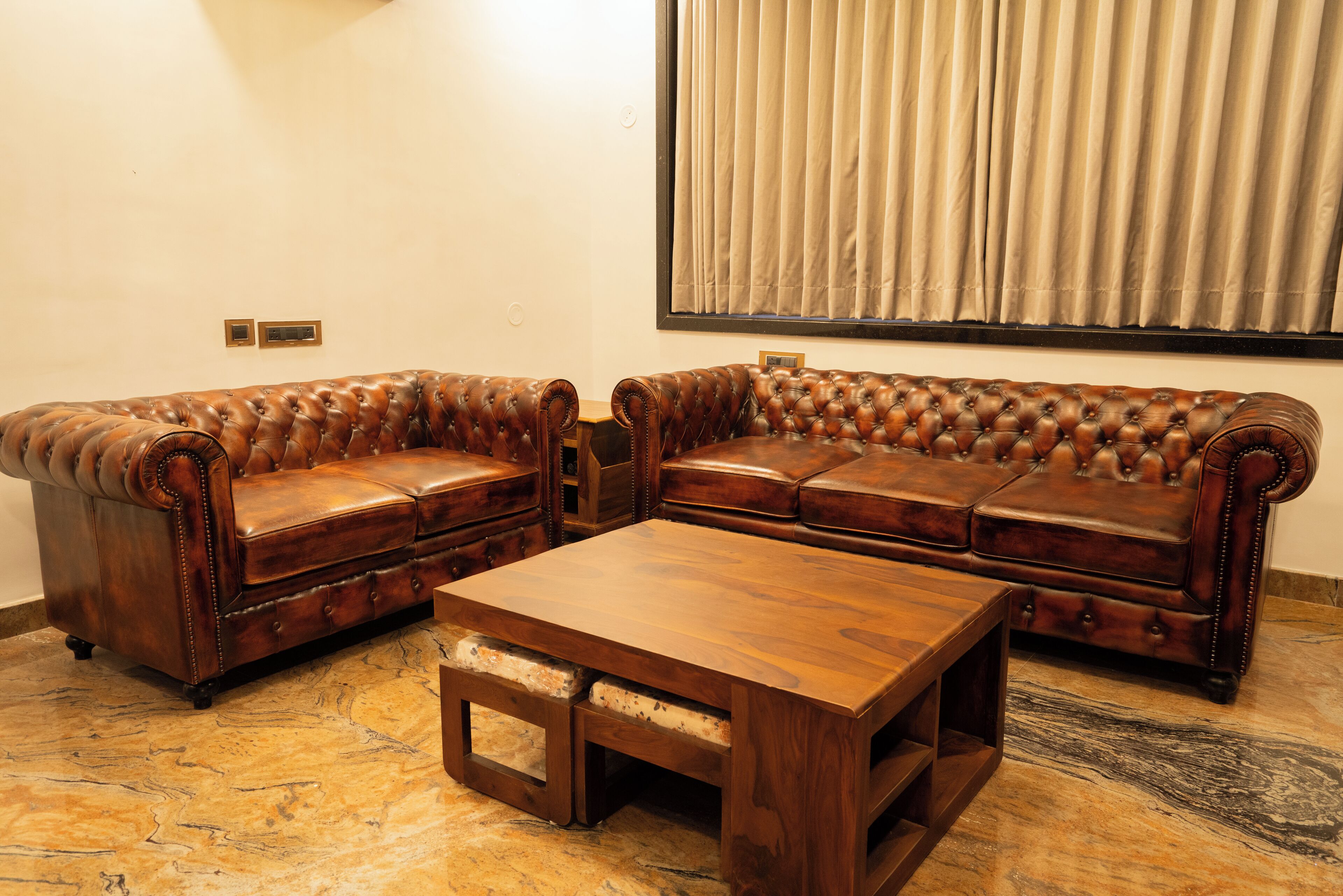 A living room with a brown leather sofa set, a wooden coffee table, and a marble floor.