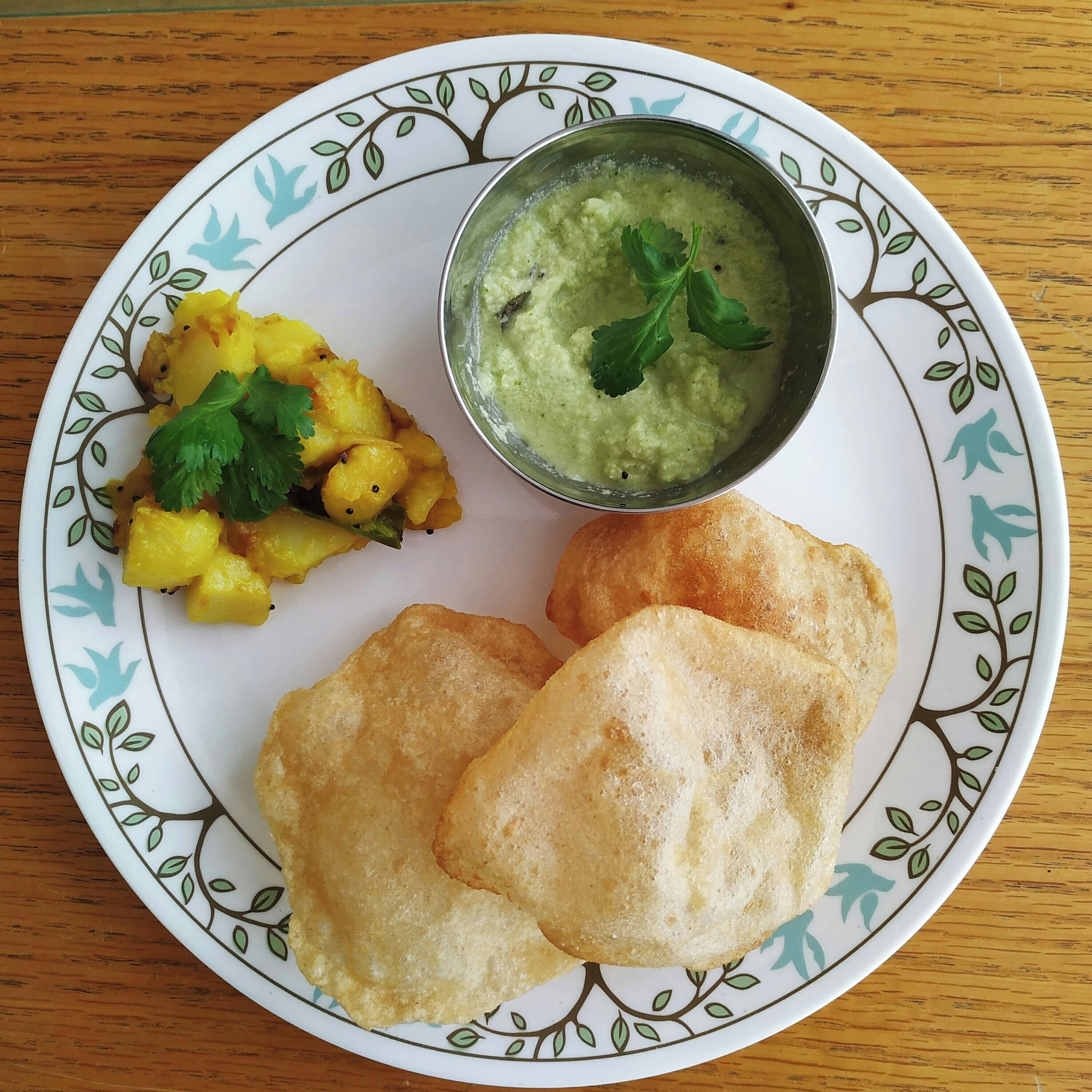A plate with two fried items, a bowl of green dip, and a side of yellow vegetable dish.