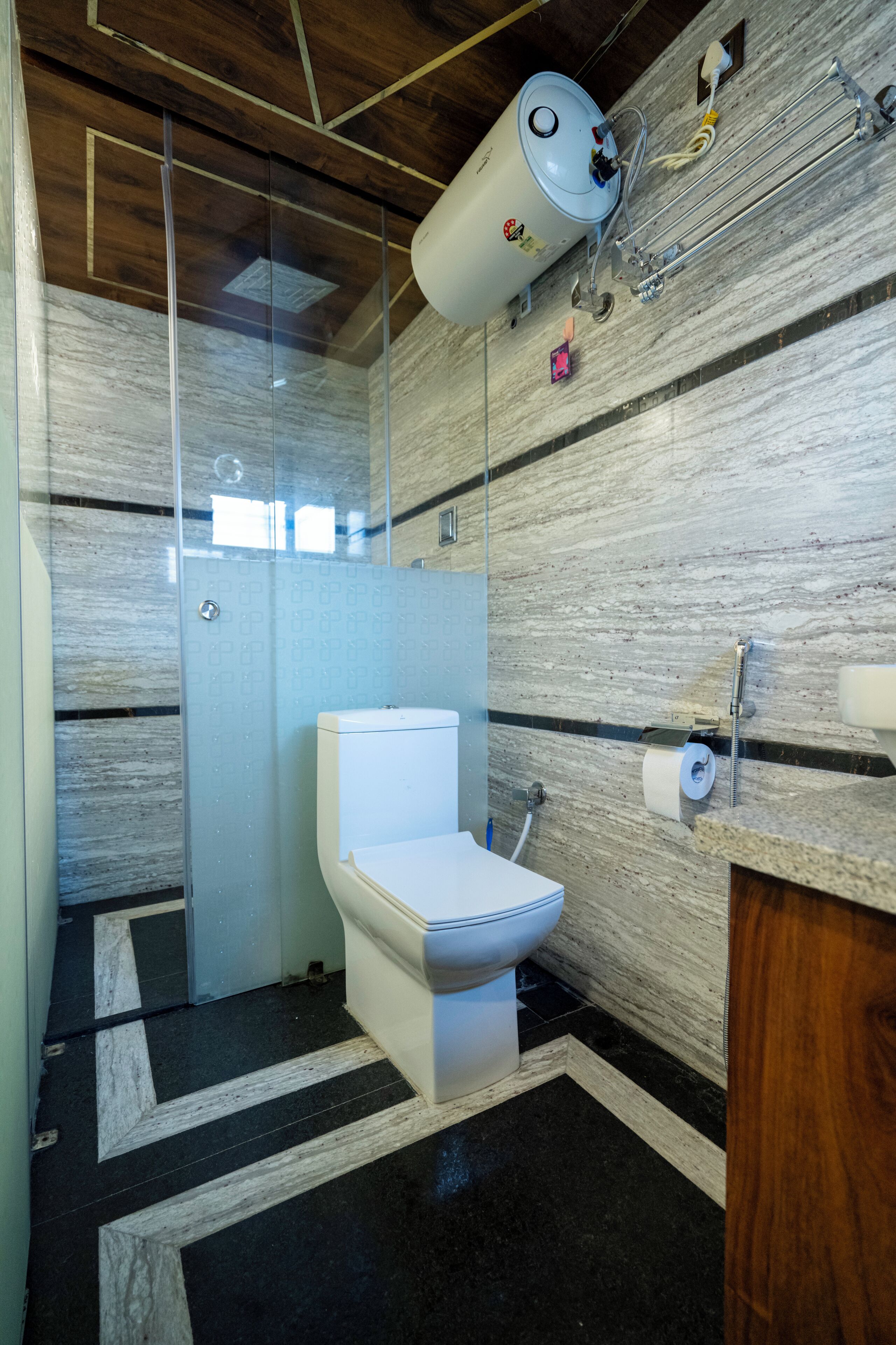 A modern bathroom with a glass-enclosed shower, a white toilet, and a wooden vanity.