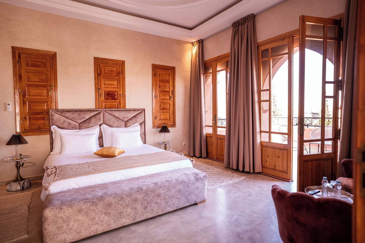 A spacious bedroom with a large bed, wooden doors, and a view of the outdoors.