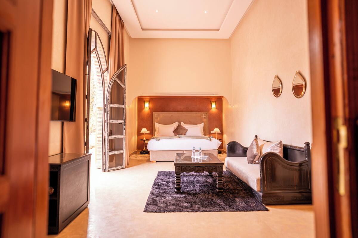 A hotel room with a large bed, a flat-screen TV, a desk, and a sofa.