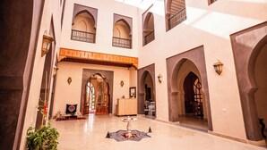 A spacious interior with high ceilings, multiple arches, and a central area with a table and chairs. - Palais Menzah & SPA (Oulad Hassoune)