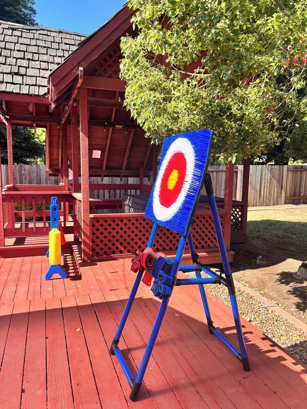 A wooden deck with a target board, a blue chair, and a yellow and red object.
