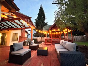 An outdoor patio with wicker furniture, a barbecue grill, and string lights.