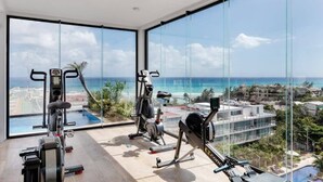 Een sportschool met fitnessapparatuur en uitzicht op de oceaan.