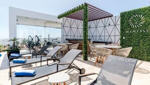Een dakterras met loungezetels, een pergola en een muur met een logo.