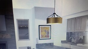 A modern kitchen with a hanging light fixture, a framed artwork, and a built-in oven.