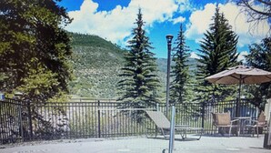 A pool area with a 3 FT depth marker, surrounded by a fence, trees, and outdoor seating.