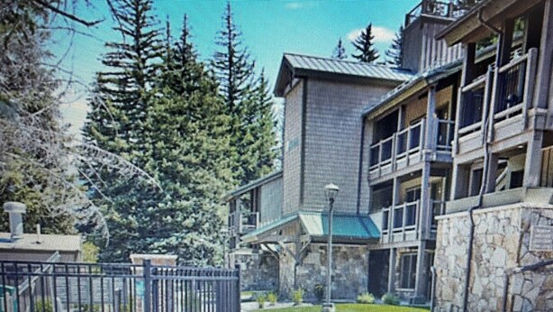 A building with a stone facade, a balcony, and a fenced area with a pathway leading to it.