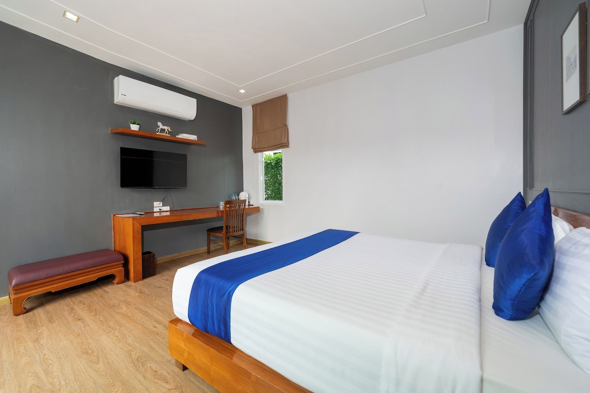A modern bedroom with a large bed, a desk, and a TV.