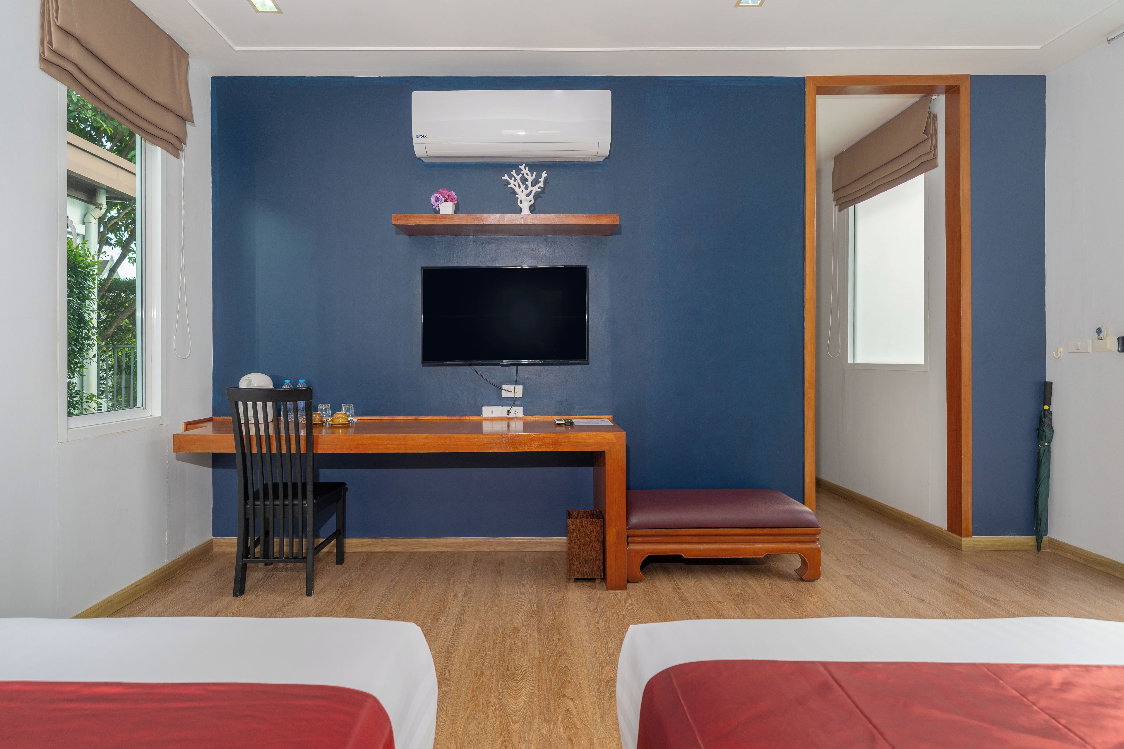 A room with a bed, a desk, a chair, a TV, and a window.