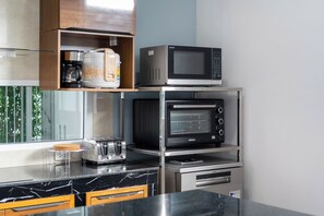 A kitchen with a microwave, toaster, and coffee maker on shelves, a marble countertop, and wooden cabinets. - Phuket La Siesta Pool Villa And Pool Access (Rawai)