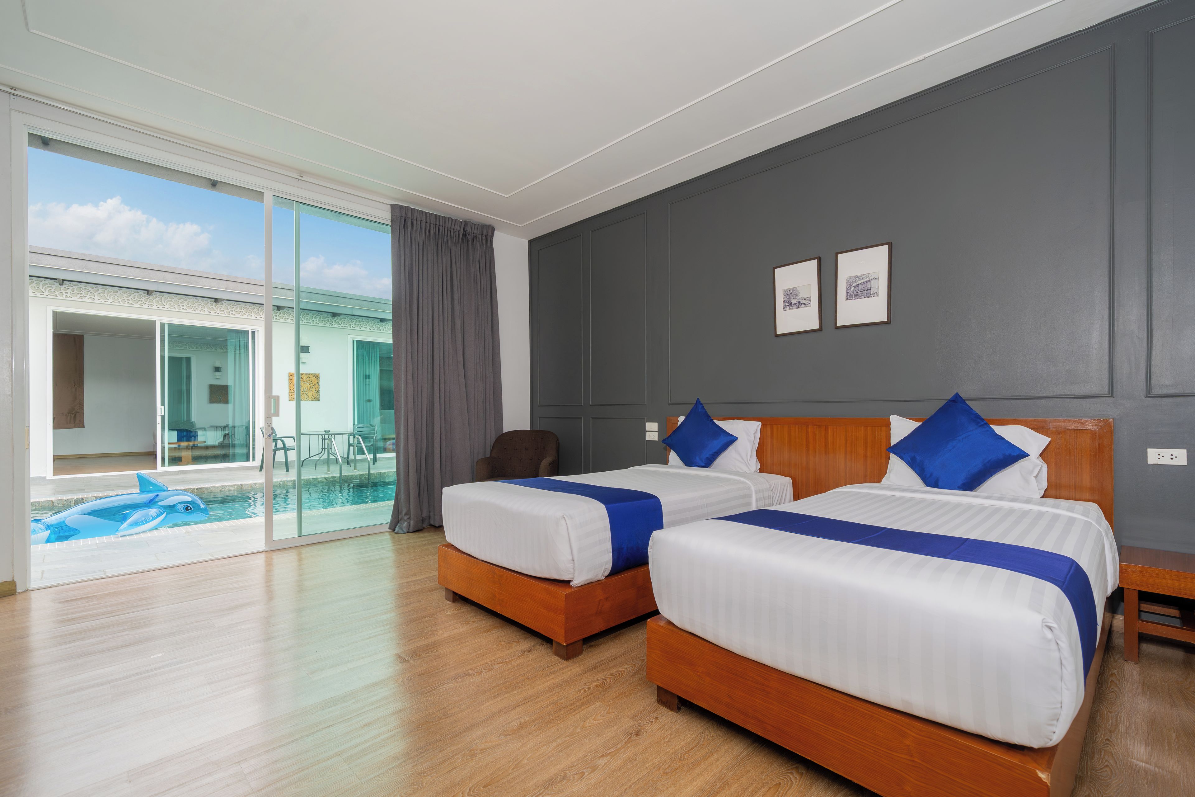 Une chambre d’hôtel avec deux lits, une grande porte-fenêtre coulissante donnant sur un balcon et une vue sur la piscine.