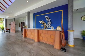 A reception area with a blue wall, a wooden reception desk, and a large column.