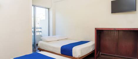 A room with two beds, a wooden desk, and a TV on the wall.