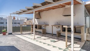 Eine Dachterrasse mit einer Pergola, Außenduschen und Kübelpflanzen.