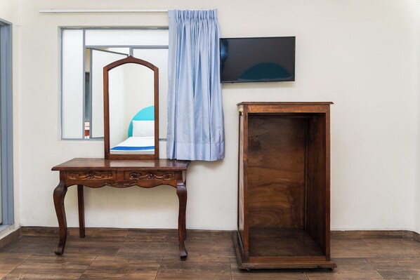 A wooden dresser with a mirror, a television mounted on the wall, and a window with a curtain. - Capital O Nueva York, Guadalajara centro (downtown) (Guadalajara)