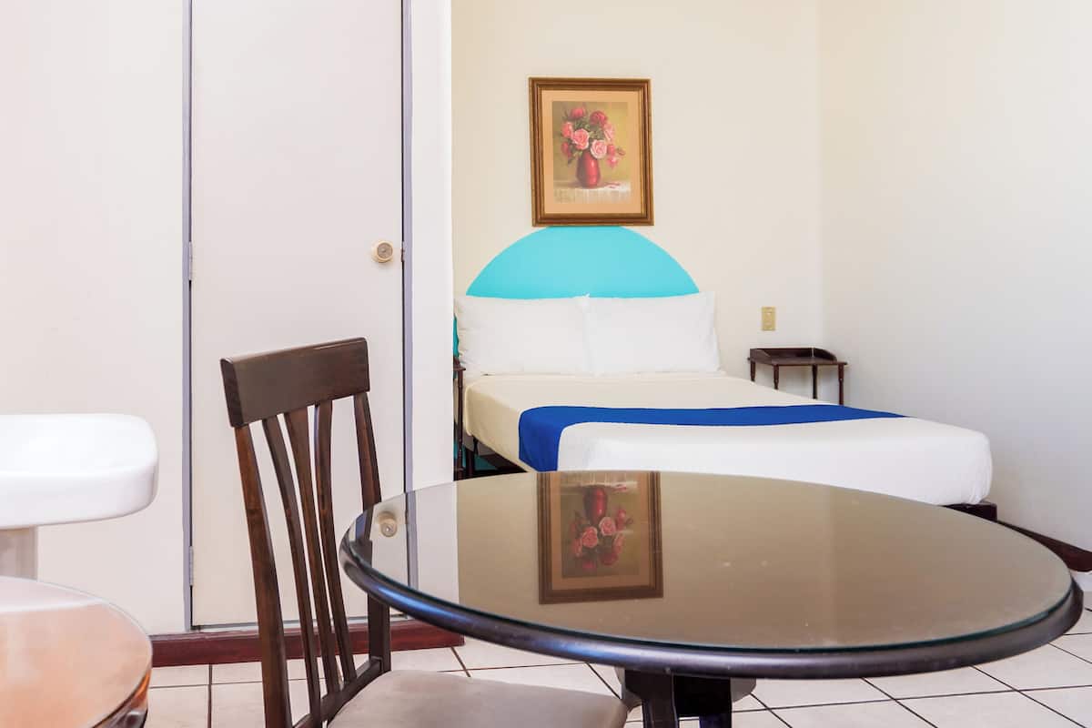 Une chambre d’hôtel avec un lit, une chaise, une table et un tableau au mur.