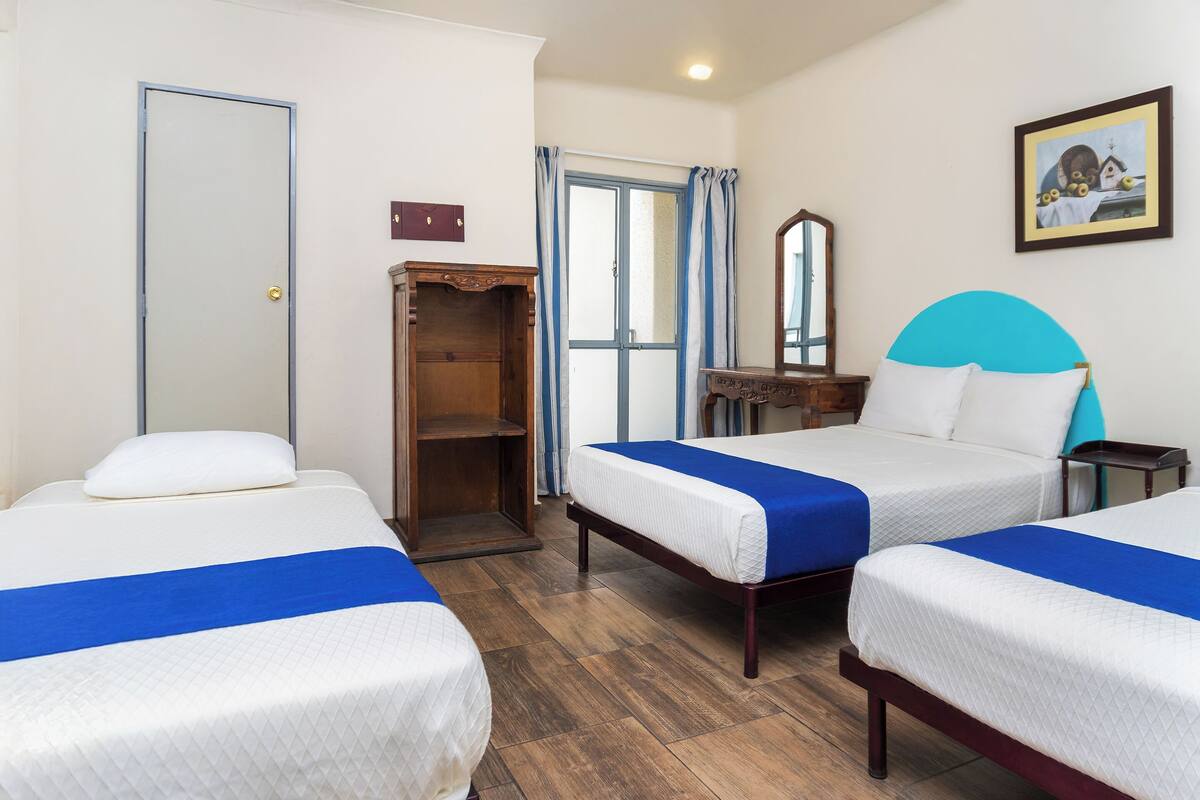 Une chambre d’hôtel avec deux lits, une armoire, un miroir et un tableau au mur.