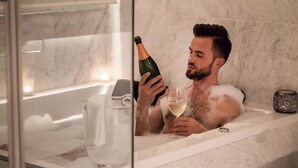 A man in a bathtub holding a bottle of champagne and a glass. - Country house in Vilamaniscle - Girona (Vilamaniscle)