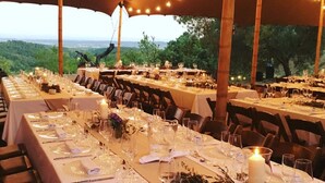 An outdoor dining area with tables set for a meal, string lights overhead, and a view of the landscape. - Country house in Vilamaniscle - Girona (Vilamaniscle)