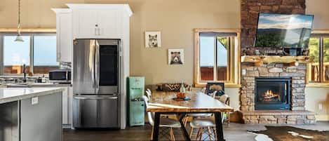 Una cocina moderna con refrigerador, estufa y comedor con mesa y sillas.