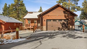 A wooden cabin with a garage, a porch, and a sign warning of coyotes.