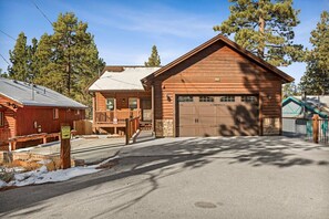 A wooden cabin with a garage, a porch, and a sign warning of coyotes. - High Altitude Retreat + Game Room + Hot Tub (Big Bear Lake)