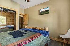 A bedroom with a bed, a chair, a painting, and a wooden door.