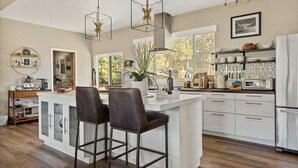 A modern kitchen with a central island, bar stools, pendant lighting, and a view of the outdoors. - LUX Guest FAV + Stunning Views + Yoga Deck + Spa (Big Bear)